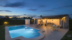 Une piscine avec des chaises longues et un espace extérieur aménagé avec des tables et des chaises.