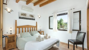 Une chambre à coucher avec un lit en bois, des lampes de chevet, une fenêtre avec des rideaux et une chaise.
