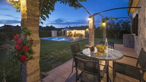 Une terrasse extérieure avec une piscine, entourée de murs en pierre et d’arbres.