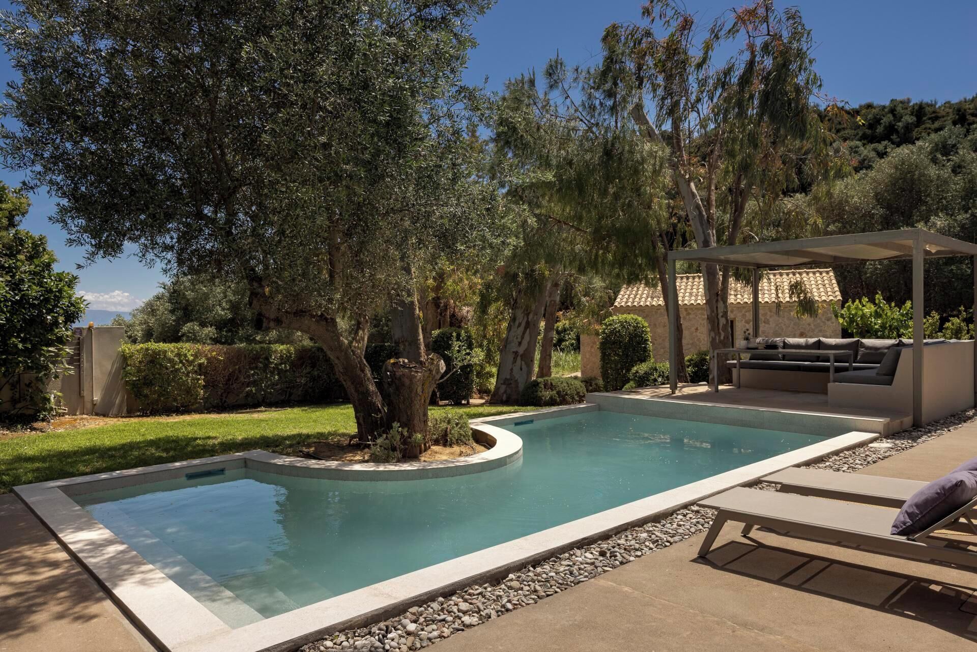 Una piscina con un pergolato e lettini da relax.