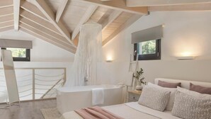 Une chambre avec un grand lit, une baignoire, une fenêtre et une structure de plafond en bois.