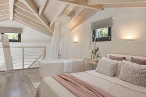 Une chambre avec un grand lit, une baignoire, une fenêtre et une structure de plafond en bois.