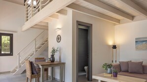 Un intérieur moderne avec un escalier, un coin repas, un canapé et une vue sur l’extérieur.