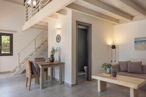 Un interior moderno con una escalera, una zona de comedor, un sofá y vistas al exterior.