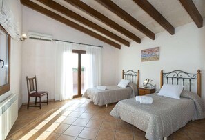 Une chambre avec deux lits, une chaise, un radiateur et un tableau au mur.