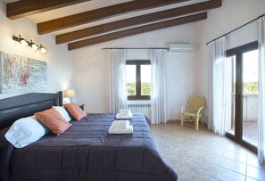 Een hotelkamer met een groot bed, een stoel, een raam met gordijnen en een airconditioning.