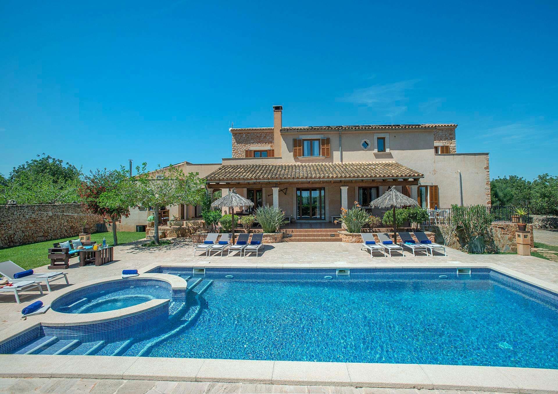 A two-story house with a swimming pool and outdoor seating.