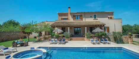 A two-story house with a swimming pool and outdoor seating.