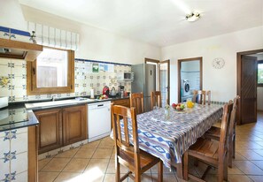 Une cuisine équipée d’une table à manger pour quatre personnes, d’un réfrigérateur, d’un four à micro-ondes et d’un lave-linge.