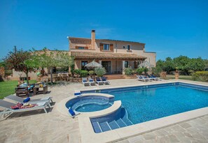 Une maison à deux étages avec une piscine, un espace salon extérieur et un jardin.