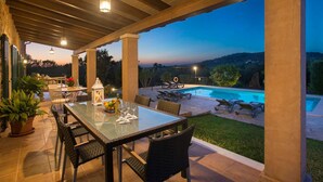 An outdoor patio with a pool, dining area, and views of the landscape.