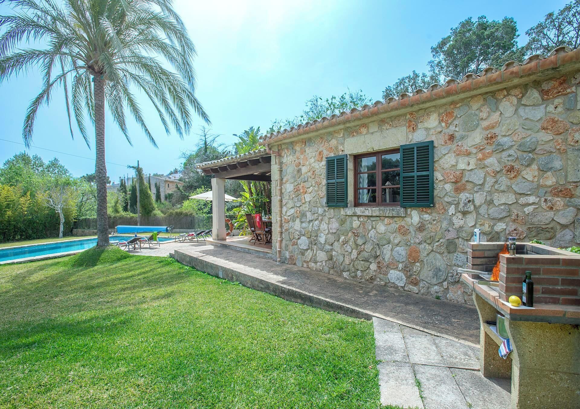 Ein Steinhaus mit Pool, Sitzgelegenheiten im Freien und Grillplatz.