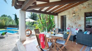 A covered outdoor area with a pool, wooden furniture, and stone walls. - Ca'n Pep - Two Bedroom Villa, Sleeps 4 (Mallorca)