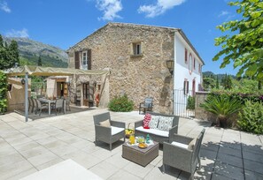A stone building with a patio area featuring outdoor furniture and a table set for dining. - Camp d'Avall - Five Bedroom Villa, Sleeps 10 (Mallorca)