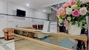 A reception desk with a digital screen, a calendar, and a floral arrangement. - Capital O 90432 Family Residence Near SCBD, Ciwalk, Mall Casablanca (Jakarta)
