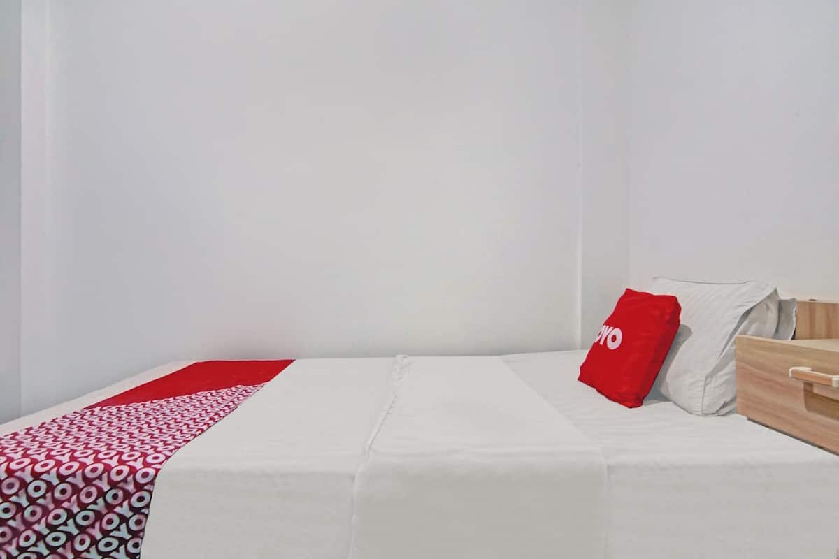 Una cama bien hecha con una colcha blanca y un corredor rojo y blanco estampado.