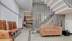 A spacious living area with a sofa and chairs, a staircase, and a kitchen in the background. - Capital O 90432 Family Residence Near SCBD, Ciwalk, Mall Casablanca (Jakarta)