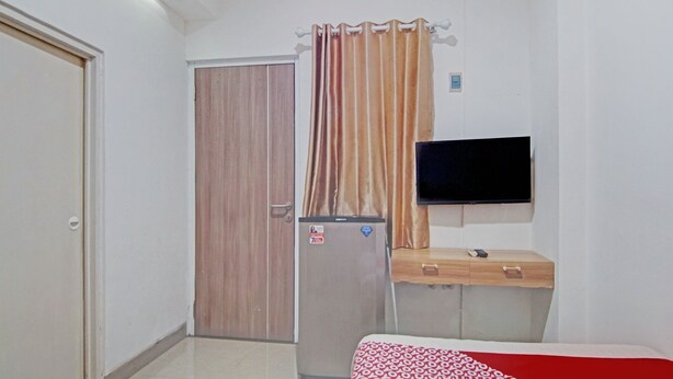 A hotel room with a bed, a TV, a wardrobe, and a refrigerator. - Capital O 90432 Family Residence Near SCBD, Ciwalk, Mall Casablanca (Jakarta)