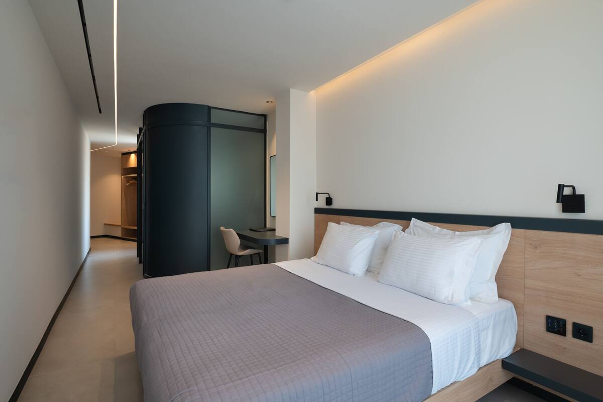 Una habitación de hotel moderna con una cama grande, un escritorio y una silla.