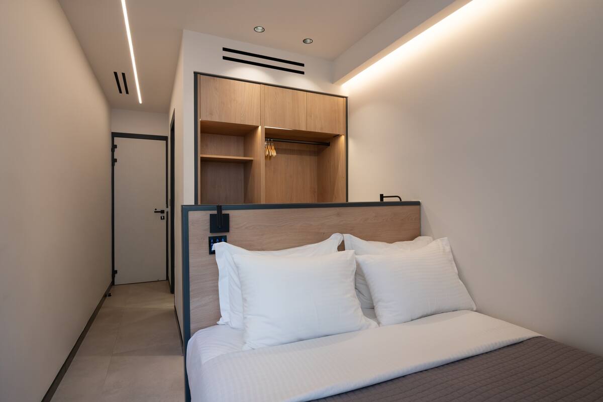 Una habitación de hotel moderna con una cama, un armario empotrado y un closet pequeño.