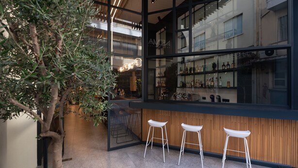 A modern bar area with a large window, wooden paneling, and three white bar stools. - Nema Hotel Athens (Athens)