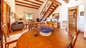 Een eetgedeelte met een houten tafel, stoelen en een trap naar een andere kamer.