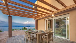 An outdoor dining area with a table set for four, overlooking a body of water.