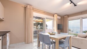 A modern living room with a dining area, large windows, and a view of the outdoors.