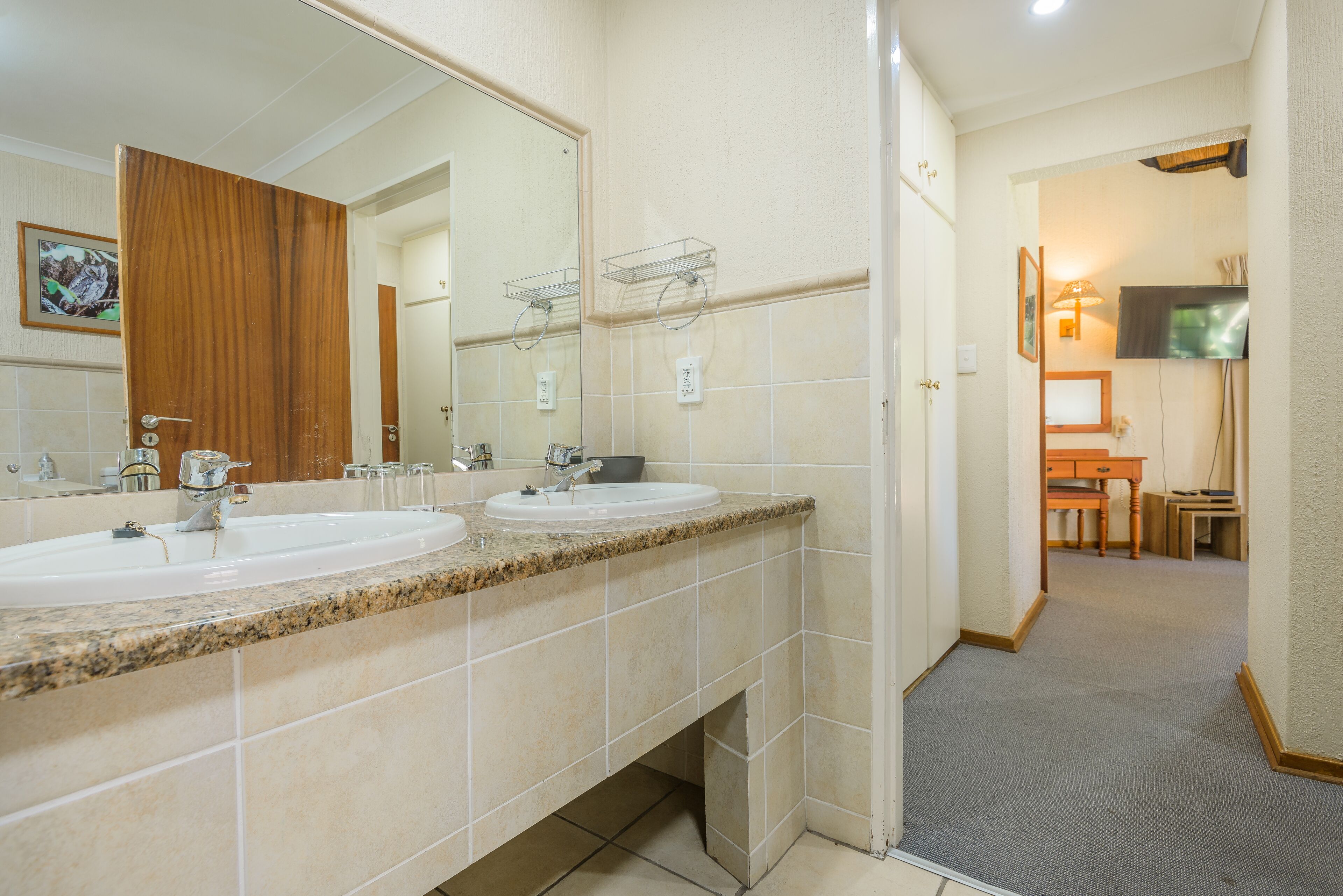 Une salle de bain d’hôtel avec deux lavabos, un grand miroir et un espace douche.