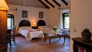 A cozy bedroom with two beds, a wooden floor, a table with a vase, and a bookshelf. - El Molino del Pilón - Five Bedroom Villa, Sleeps 10 (Arcos de la Frontera)