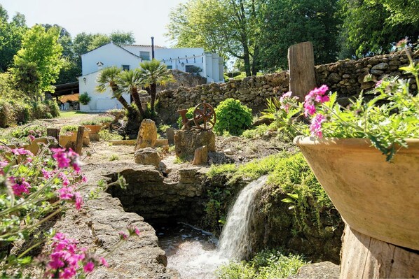 Un jardin agrémenté d’une petite cascade, de murs en pierre et de plantes en pot.