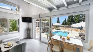 Une chambre moderne avec vue sur la piscine, un coin repas avec des chaises et un téléviseur fixé au mur.