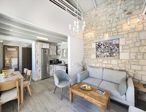 A modern living space with a dining area, kitchen, and a stone wall with artwork.