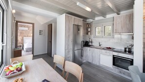 Moderni keittiö, jossa on puukalusteet, sisäänrakennettu uuni ja ruokailutila, jossa on pöytä kahdelle.