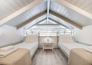 A room with a sloped ceiling, two beds, a nightstand, and a lamp. - Mirto - Three Bedroom Villa, Sleeps 6 (Tsoukalades)