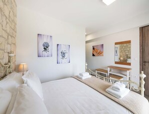 A hotel room with a bed, a bedside table, a lamp, and artwork on the walls.