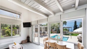 A modern interior with a pool view, a dining area, and a television. - Mirto - Three Bedroom Villa, Sleeps 6 (Tsoukalades)
