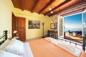 Un dormitorio con cama, puerta de madera, perchero, un cuadro y balcón con vistas.