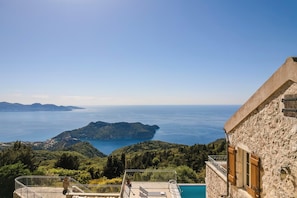 A stone building with a pool and a view of the sea.