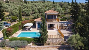 A two-story villa with a swimming pool, a covered patio, and a view of the surrounding landscape.