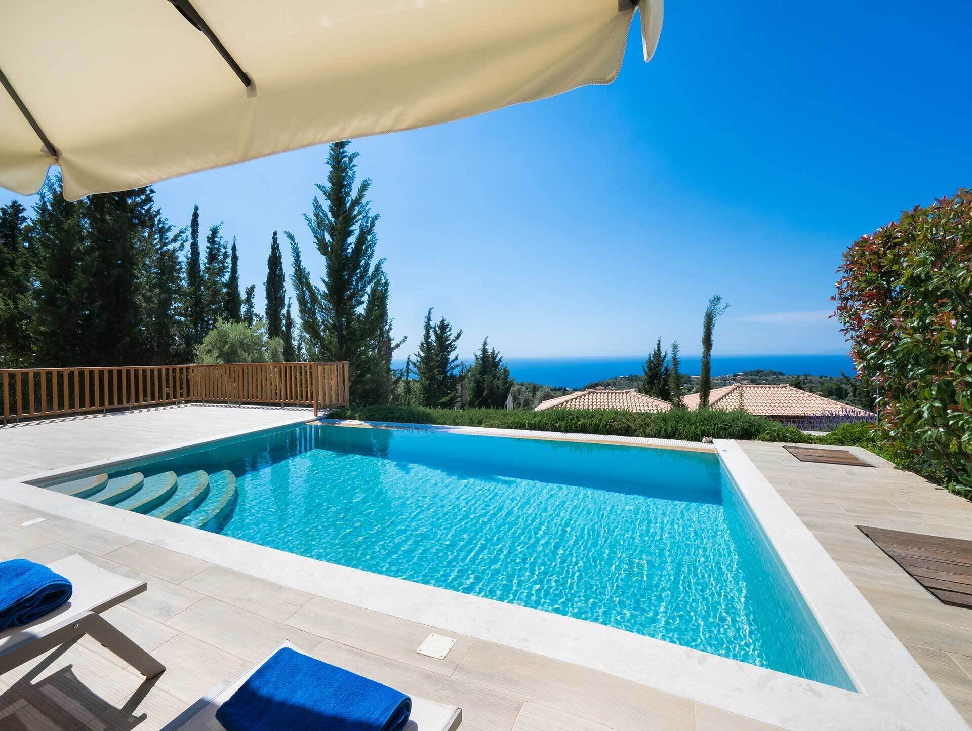 Une piscine rectangulaire à l’eau d’un bleu limpide, entourée d’une terrasse en bois et d’une clôture en bois.