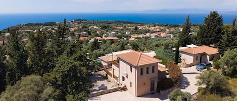 A coastal residential area with houses, a paved driveway, and a view of the sea.