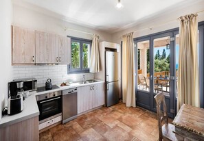 Eine moderne Küche mit Backofen, Mikrowelle und Geschirrspüler. Ein großes Fenster mit Vorhängen und ein Essbereich mit Tisch und Stühlen.