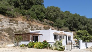 A white building with a patio, surrounded by a garden with various plants and flowers. - Casa Bellota - One Bedroom Villa, Sleeps 2 (Vejer de la Frontera)
