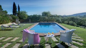 A rectangular swimming pool with lounge chairs and a table with drinks, surrounded by a grassy area and trees. - Ca'n Paner - One Bedroom Villa, Sleeps 2 (Mallorca)