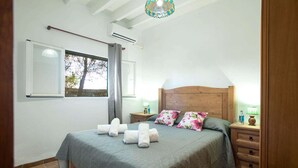 A bedroom with a bed, two bedside tables, a window, and a chandelier. - Talati de Dalt - Five Bedroom Villa, Sleeps 8 (Alaior)