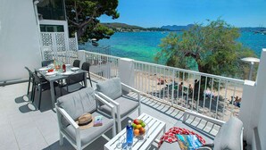 A balcony with outdoor furniture, a dining table set, and a view of the sea and beach. - Pine Walk Apartment - Three Bedroom Villa, Sleeps 5 (Mallorca)