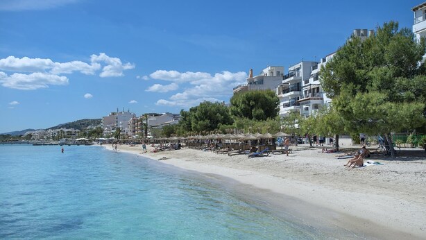 A beach with clear blue water, umbrellas, and people relaxing. - Pine Walk Apartment - Three Bedroom Villa, Sleeps 5 (Mallorca)