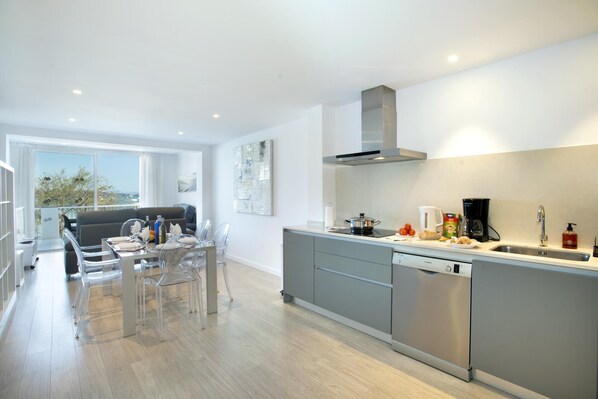 A modern kitchen with grey cabinets, a stainless steel dishwasher, and a large window overlooking a scenic view.