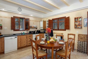 A kitchen with wooden cabinets, a dishwasher, and a dining table with chairs.